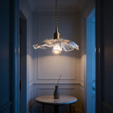 Brass pendant light with ribbed glass flower shade above a marble hallway table