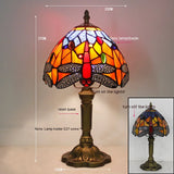Stained glass dragonfly lamp lit in a dark room