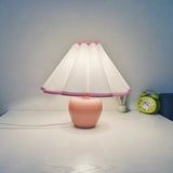 Apple ceramic lamp with pleated shade lit in a bedroom