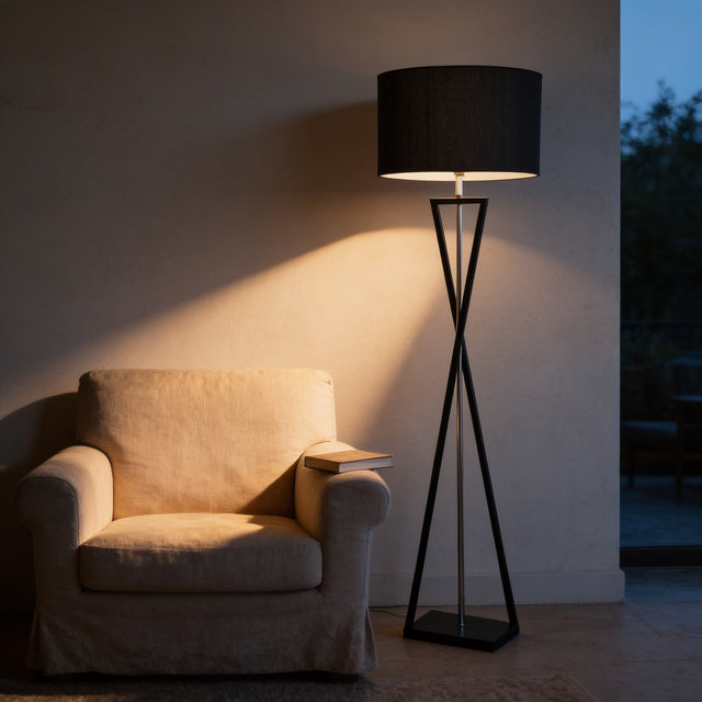 Black drum shade floor lamp on a twisted metal base beside a linen armchair