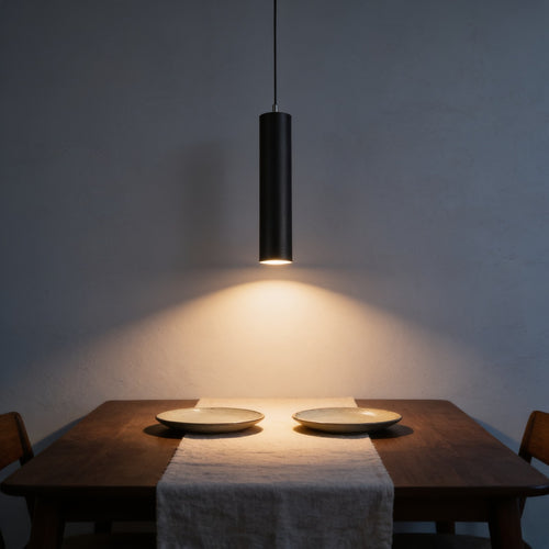Black LED cylinder pendant light hanging low over a walnut dining table