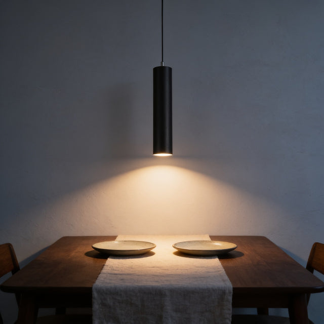 Black LED cylinder pendant light hanging low over a walnut dining table