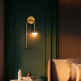 Brass ring and glass globe wall sconce on a dark green panelled wall