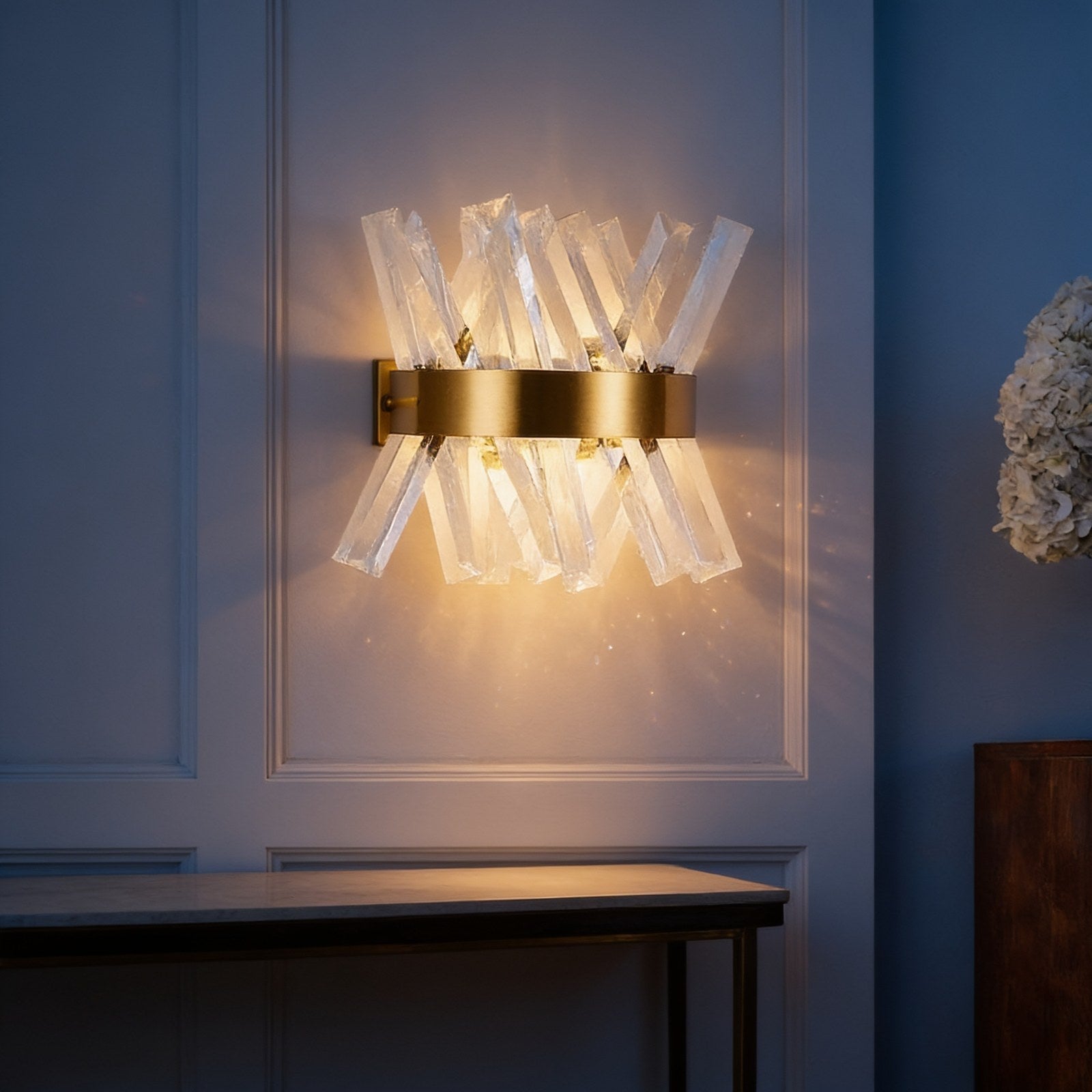 Crystal wall sconce with brass band throwing refracted light on a panelled wall