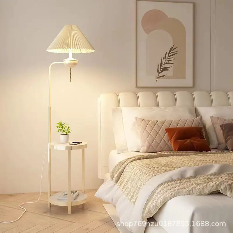Cream pleated shade floor lamp beside a bed