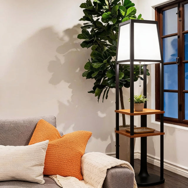 Black frame floor lamp with wooden shelves and white fabric shade beside a sofa
