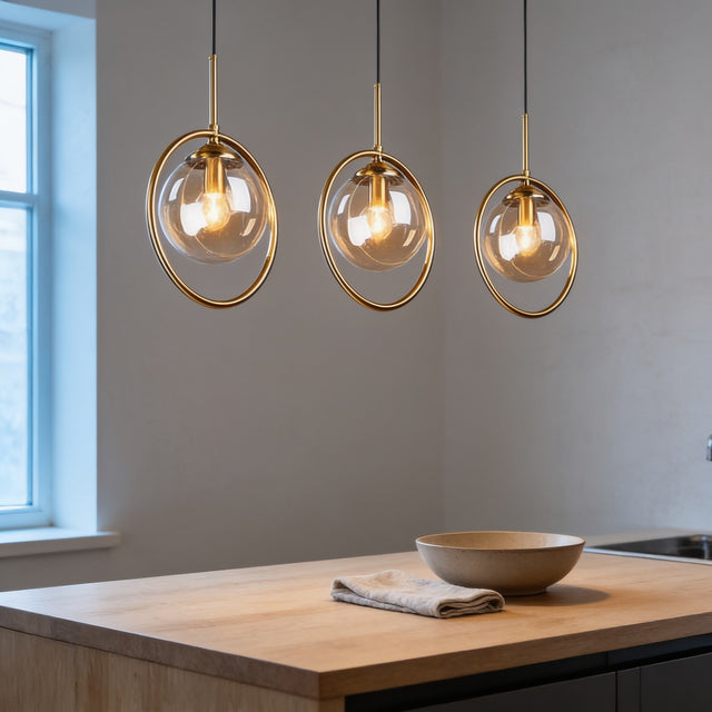 Three glass globe pendant lights with brass rings above a kitchen island