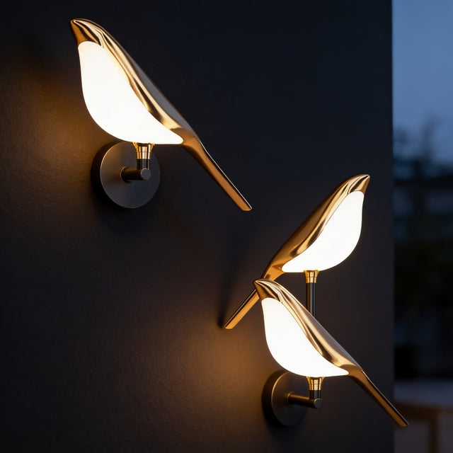 Gold bird wall sconces with glowing wings mounted on a dark charcoal wall