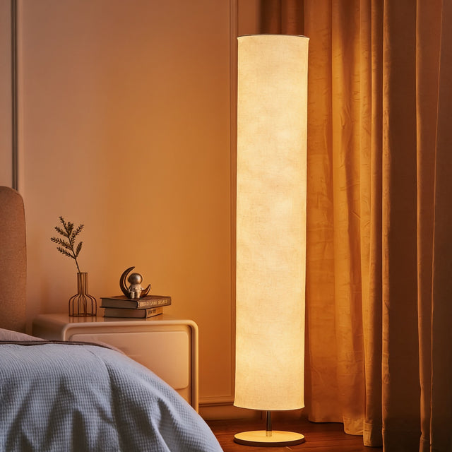Tall fabric column LED floor lamp glowing warm in a bedroom corner