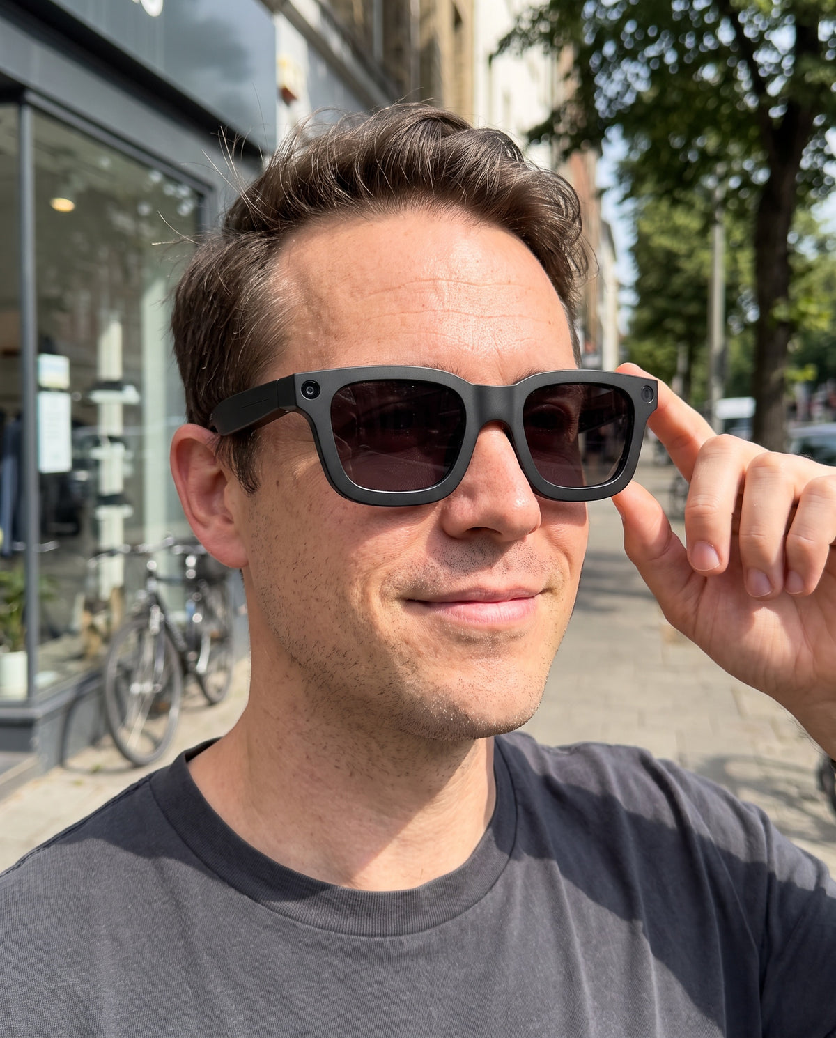 Man wearing the E03C AI smart glasses on a city street, touching the temple to change the tint