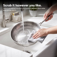 Rinsing the pan clean under a tap, with no coating to protect