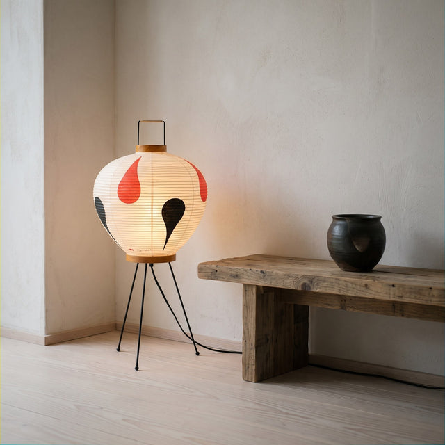 Japanese rice paper floor lantern with red and black motif on a black iron tripod