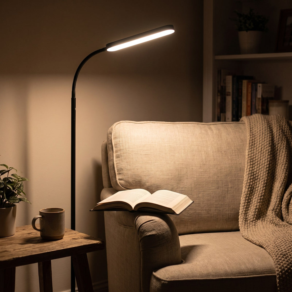 Black LED gooseneck reading floor lamp angled over an armchair with an open book