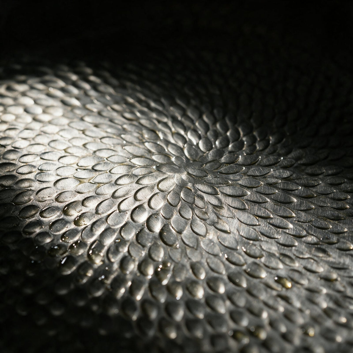 Macro close-up of the hammered fish-scale texture pressed into the titanium cooking surface
