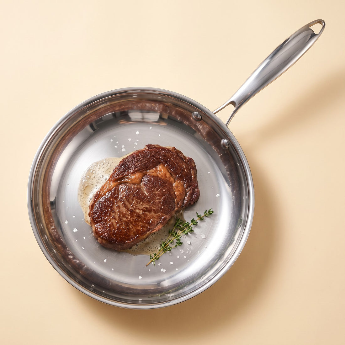 A seared ribeye resting in the stainless steel steak pan
