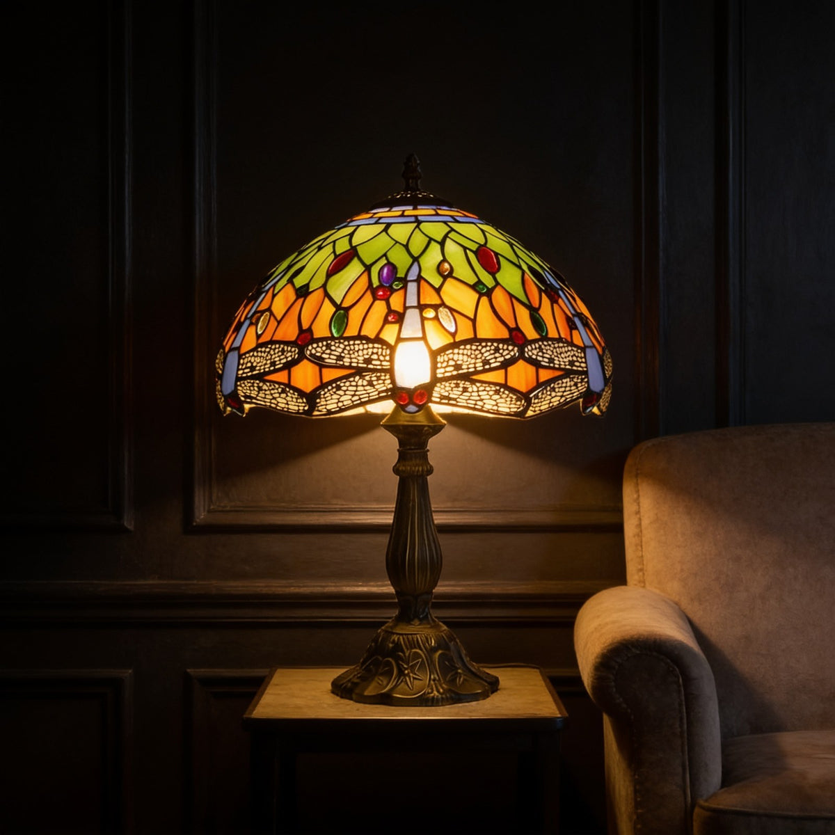 Tiffany stained glass dragonfly table lamp lit beside an armchair