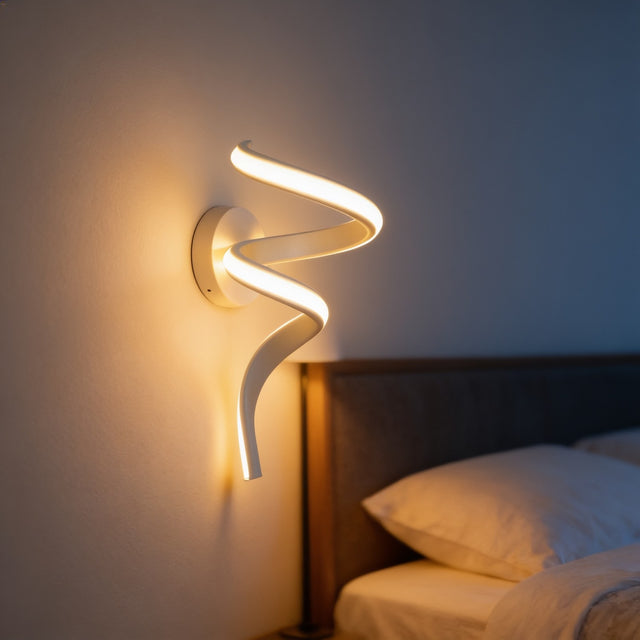 Curved ribbon LED wall sconce glowing beside a bed