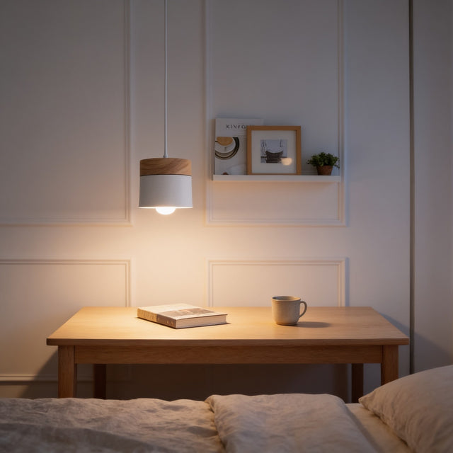 White cylinder pendant light with oak wood cap above a bedside table