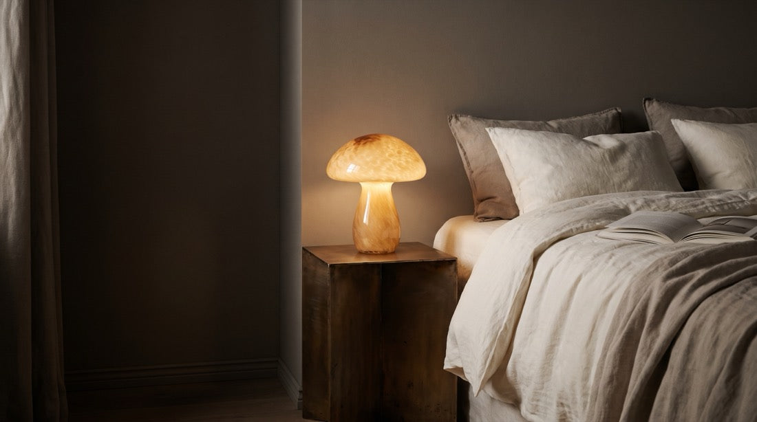 Glass mushroom lamp glowing beside a bed at night